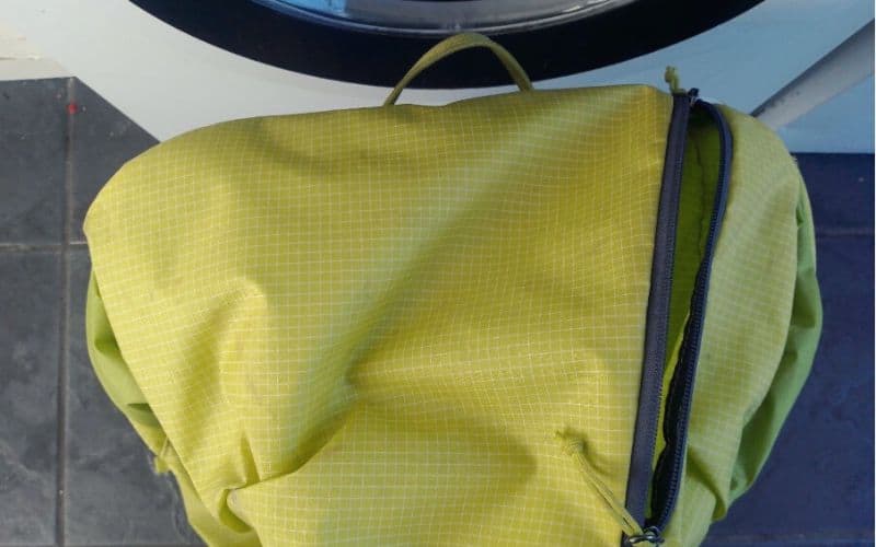 Empty pocket of backpack in front of washing machine
