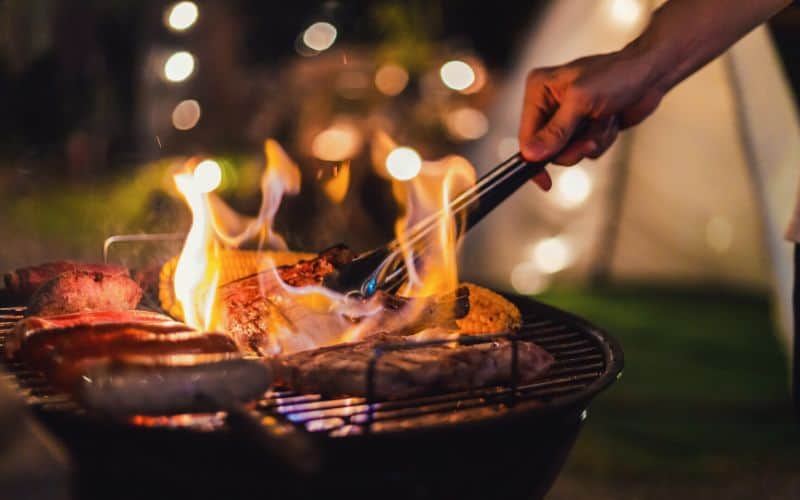 Grilling meat on a bbq grill in front of a tent