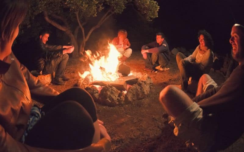 Group of adults around campfire playing Empire