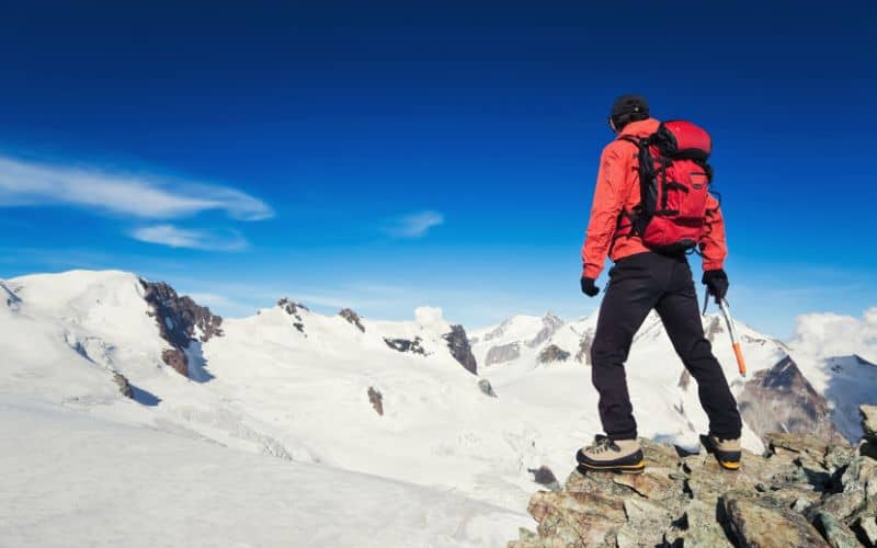 Hiker at summit of snowy mountain