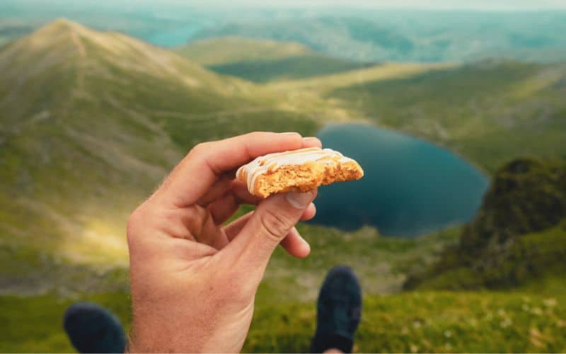 Holding up a granola bar in front of a lake