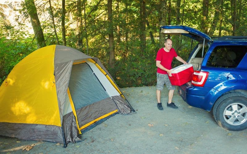 Man unpacking car parked next to tent