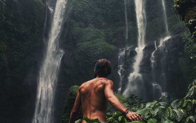 Naked hiker at bottom of a waterfall