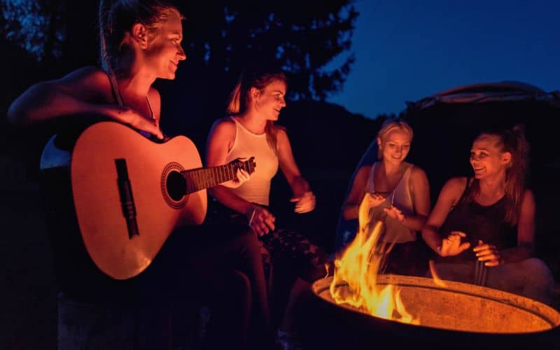 Playing name that song with a guitar round a campfire