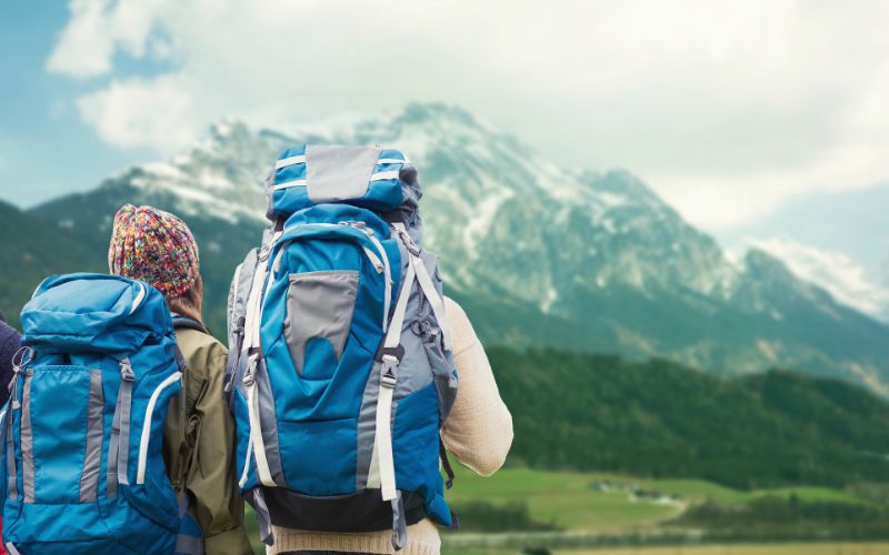 Two hikers wearing large backpacks looking at a faraway mountain