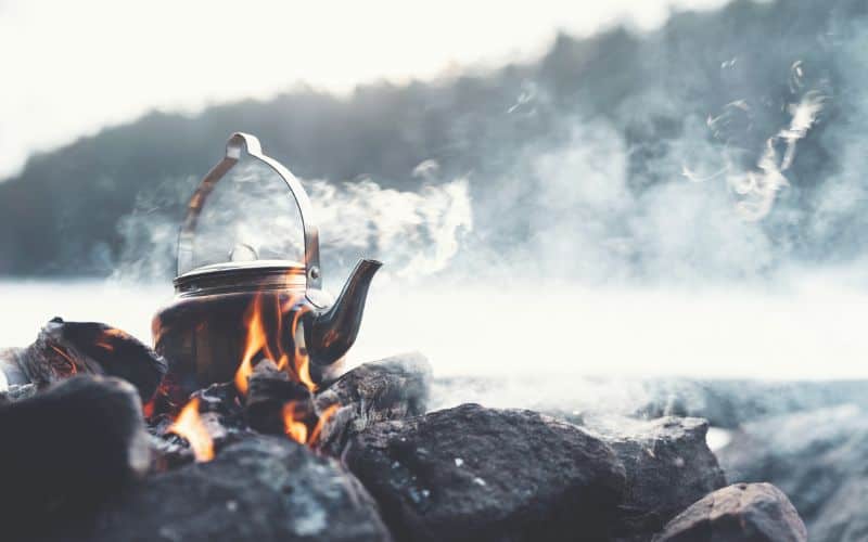 Kettle of water boiling over a campfire