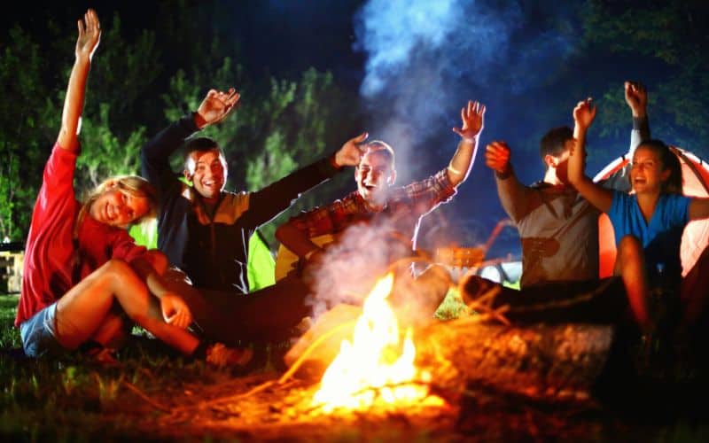 Camping group of friends having fun round a campfire
