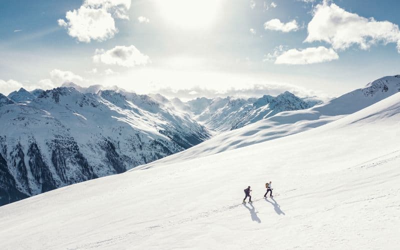 Two hikers hiking across snowy mountain
