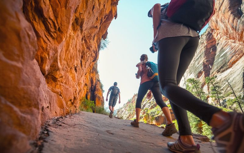 Ground shot of hiker walking along a red rock wall