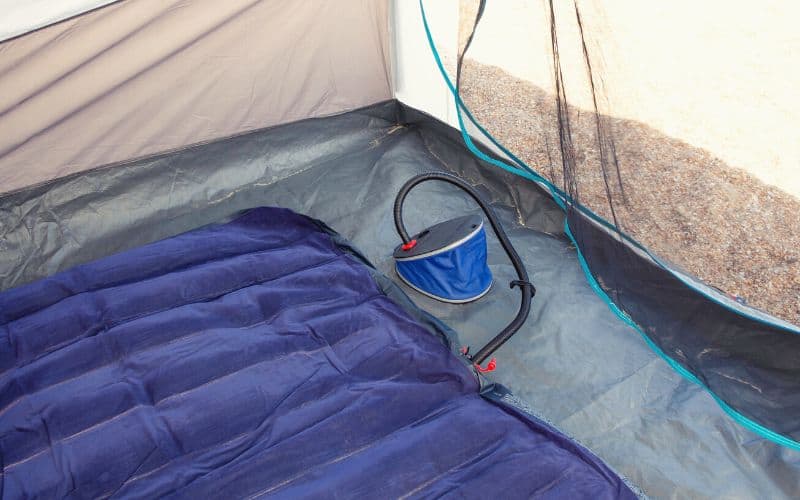 An air mattress being inflated inside a tent with a foot pump