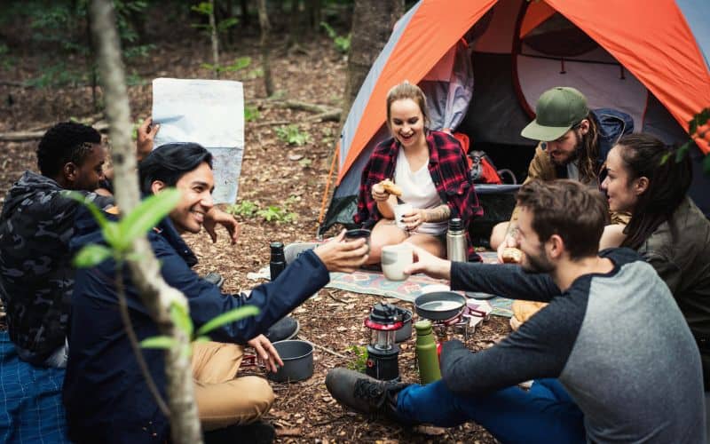Group of camping friends hanging out in front of their tent