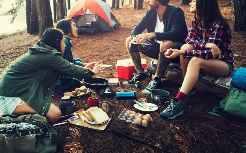 Camping friends cooking dinner on a camp stove