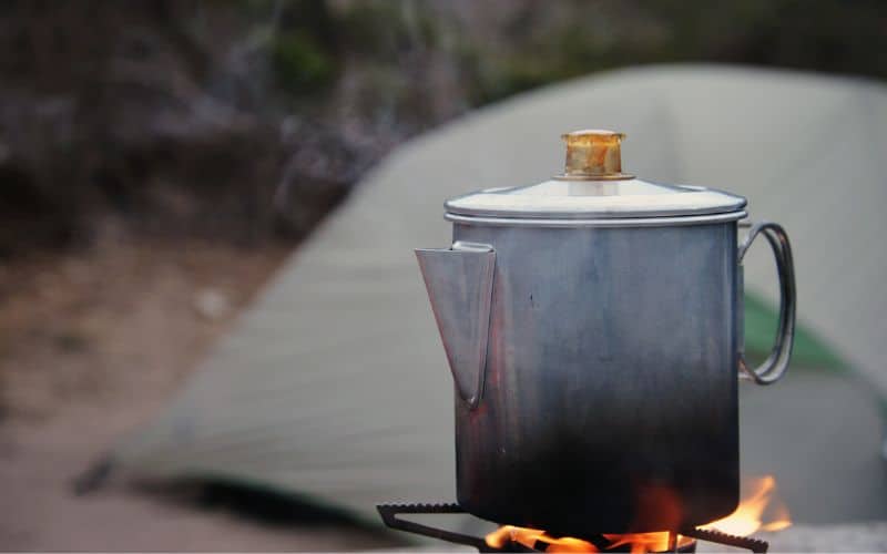 Coffee pot sitting on top of a lit camp stove