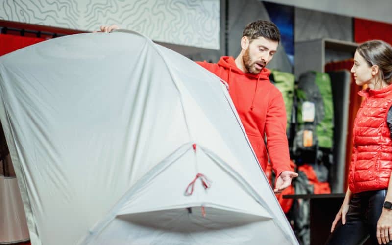 Employee at camp store showing woman a tent