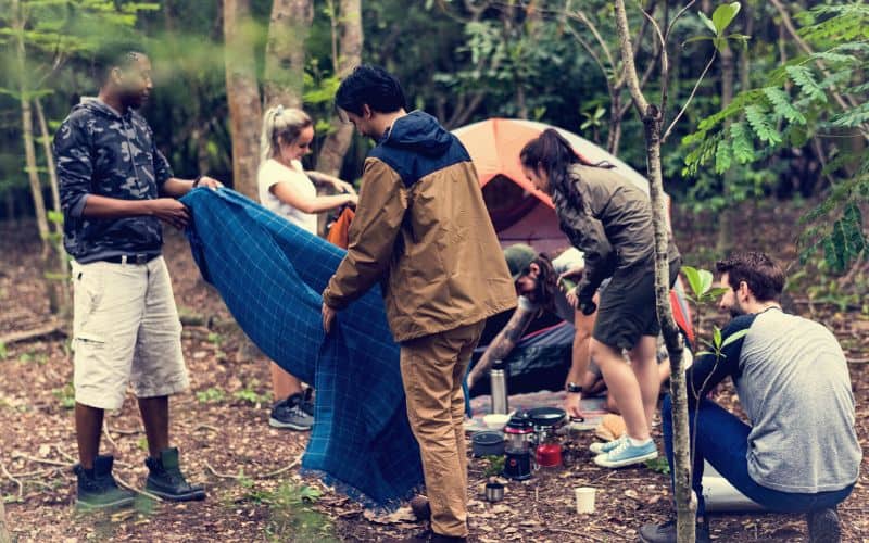 Friends tidying up campsite after eating together