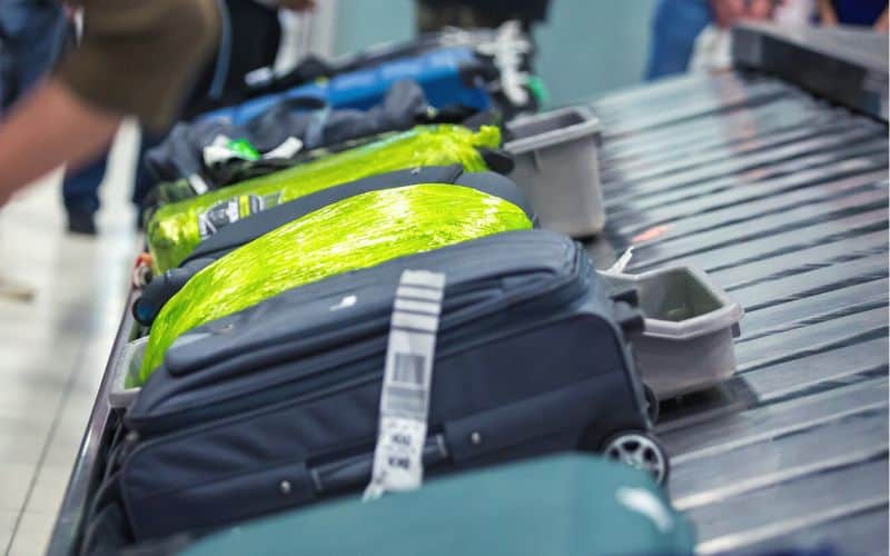 Luggage, including bags wrapped in plastic, on an airport carosel