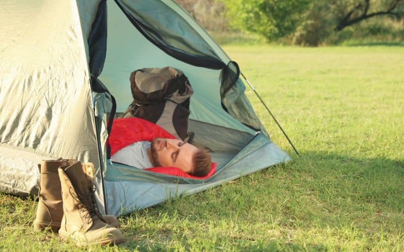 Man sleeping on his back inside a tent