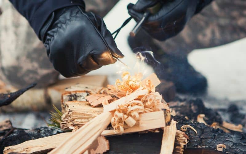 Man starts a campfire using a ferro rod to create sparks