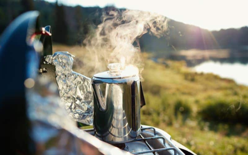 Steam rising from a camping coffee percolator sitting on a camp stove