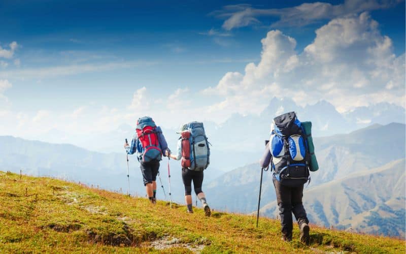 Three backpackers with large backpacks on hiking in mountains