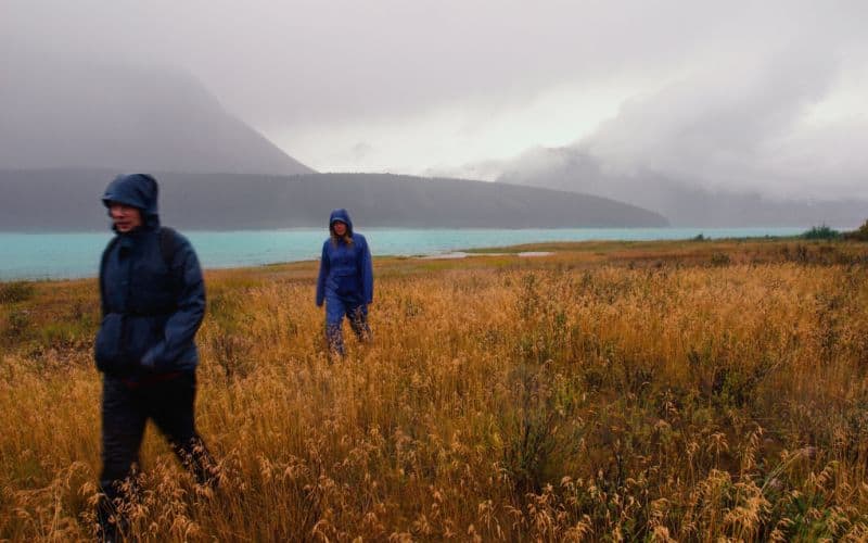 Two hikers hiking across a field in the rain