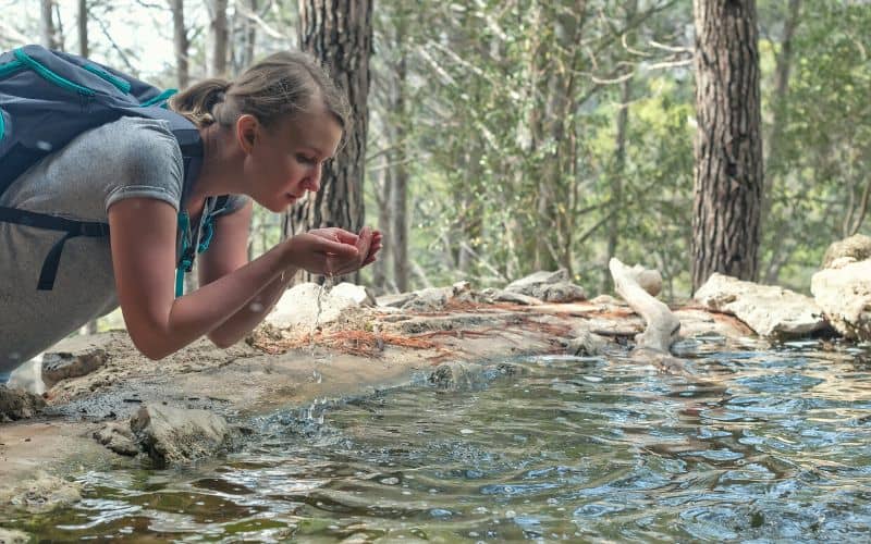 Woman drinking directly from a water source