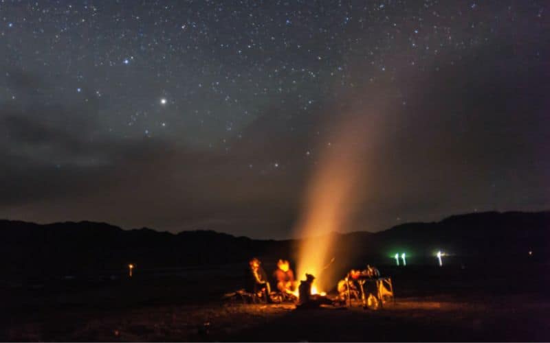 Group sitting around campfire under a starry sky