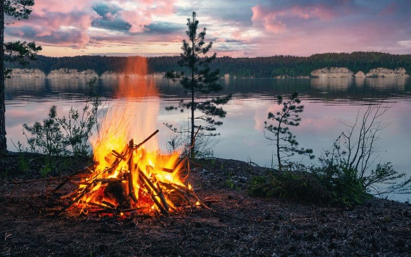 Campfire on the banks of a river at sunset