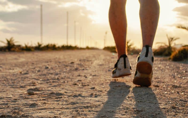 Close up of mans feet going for a jog on sandy ground