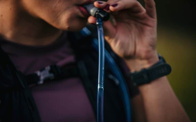 Close up of someone drinking water through a hydration pack tube