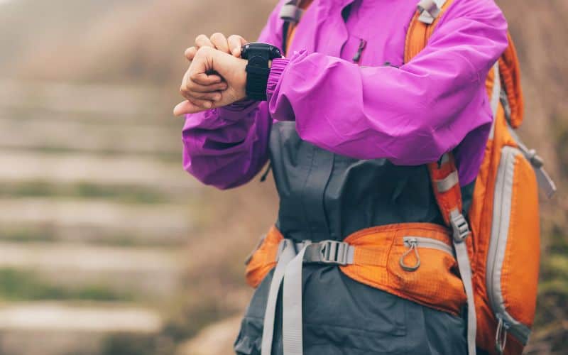 Hiker at the bottom of stairs checking her fitness watch 