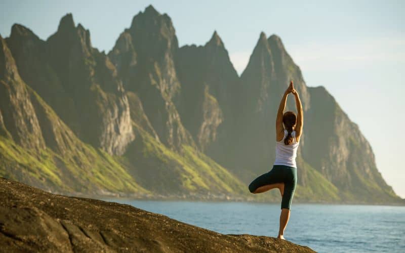 Woman doing a yoga balance in front of mountains