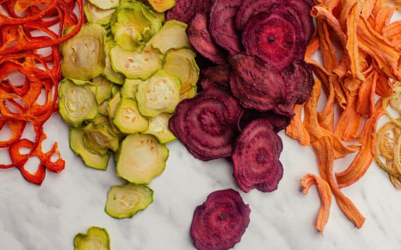 Selection of dehydrated vegetable slices laid out over table