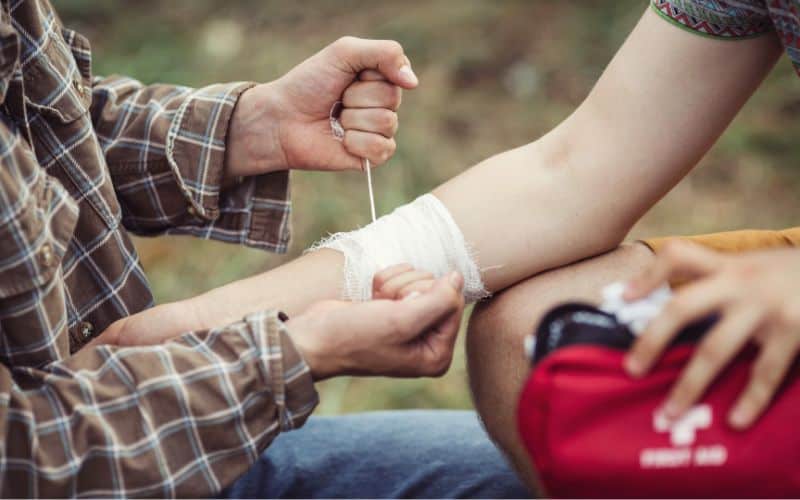 Hiker tying bandage onto another hikers arm