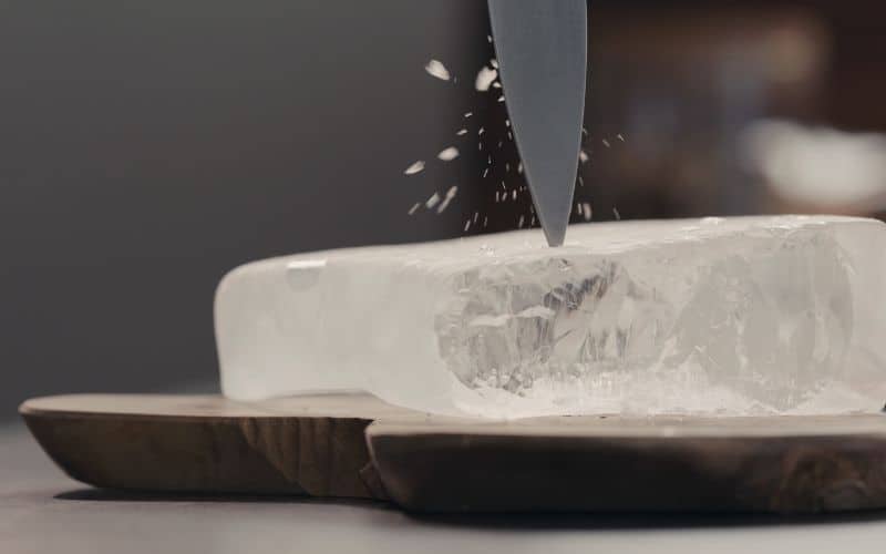 Knife cutting into a large, rectangular block of ice