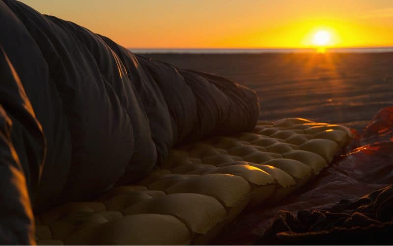 Person lying on textured sleeping pad on a beach