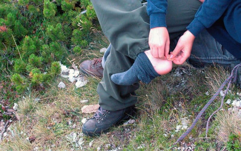 Person removing tape from foot after day of hiking 