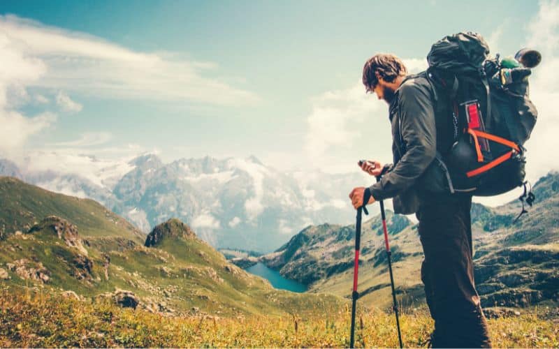 Backpacker looking at GPS in front of a mountain scene 