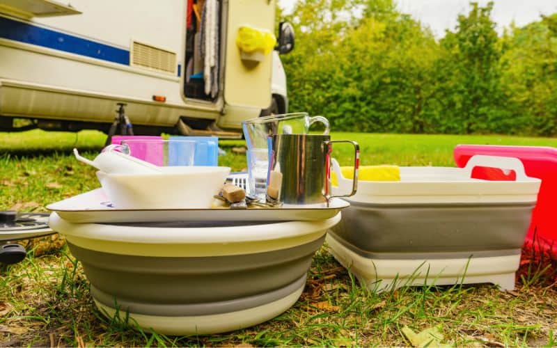 Camping washing up, dishes sitting on top of collapsible basins