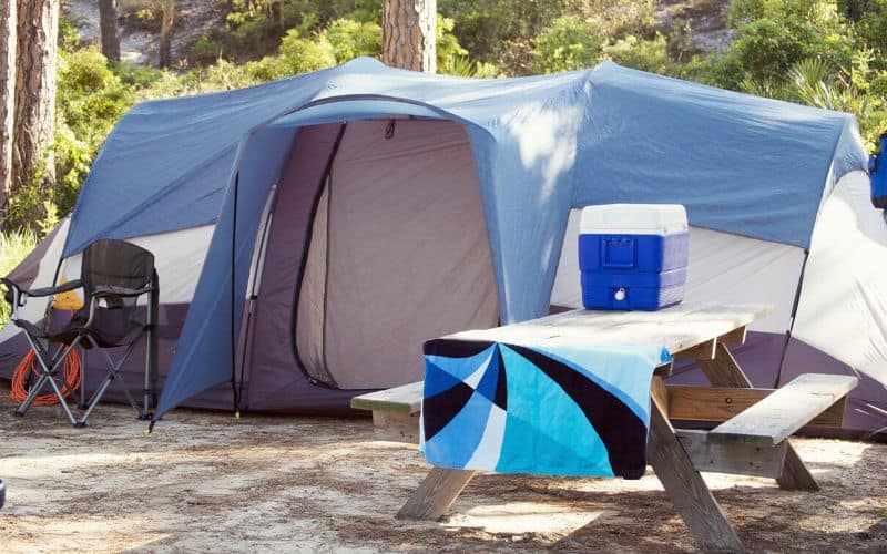 Cooler sitting on picnic table beside a pitched family tent