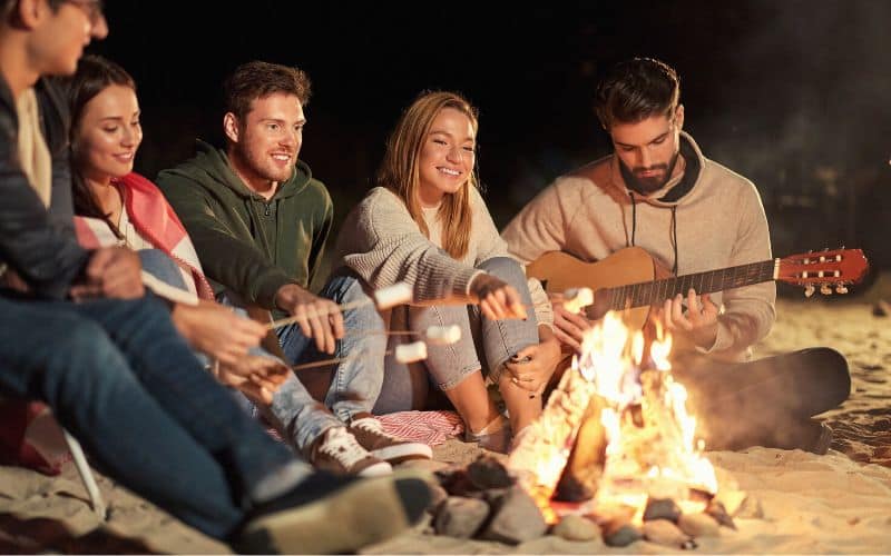 Group of campers around campfire on beach