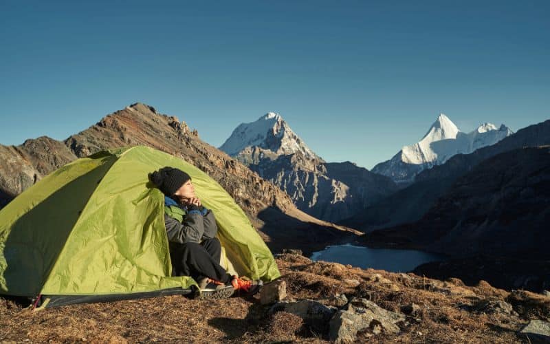 Woman sitting in tent staring at mountains in distance