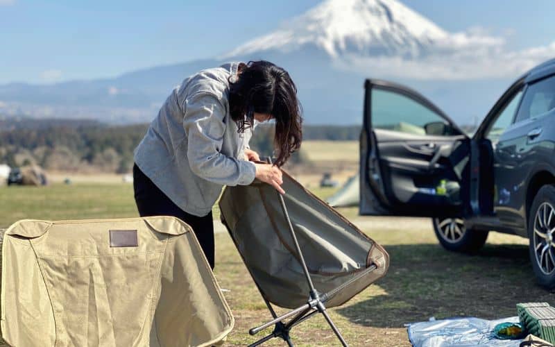 Woman unfolding camping chairs in front of mountain