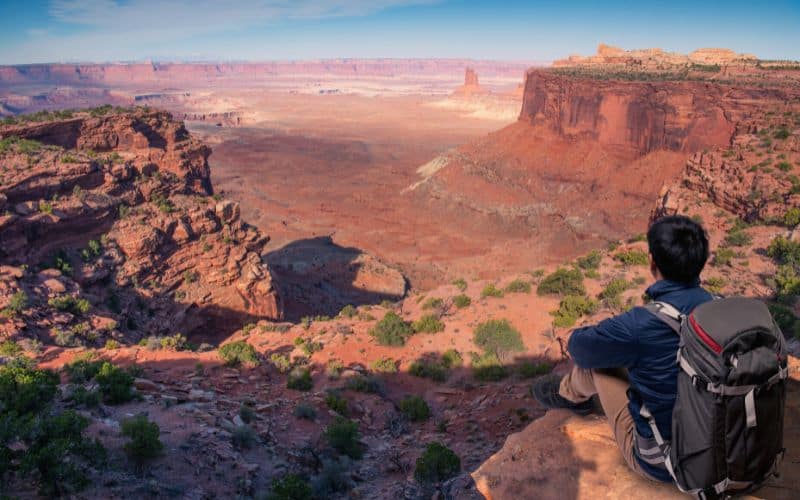 Backpacker sitting on cliff edge at Grand Canyon