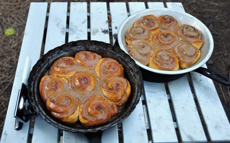 Cinnamon rolls in pans sitting on a camp table