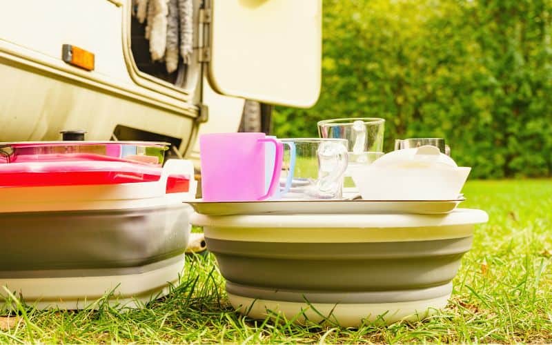 Collapsible basins filled with dishes outside a caravan