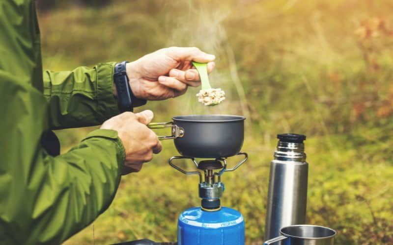 Man cooking porridge on a camping stove